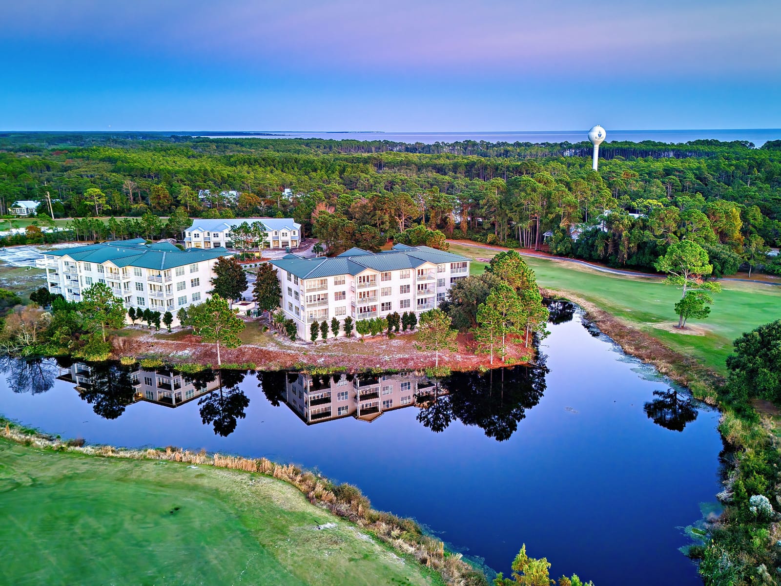 Aerial view of the St. James Bay resort condos reflected in the pond beside the golf course at twilight in Carrabelle, Florida