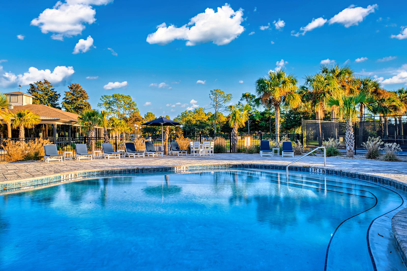 Resort swimming pool framed by palm trees under a blue sky at St. James Bay in Carrabelle, Florida